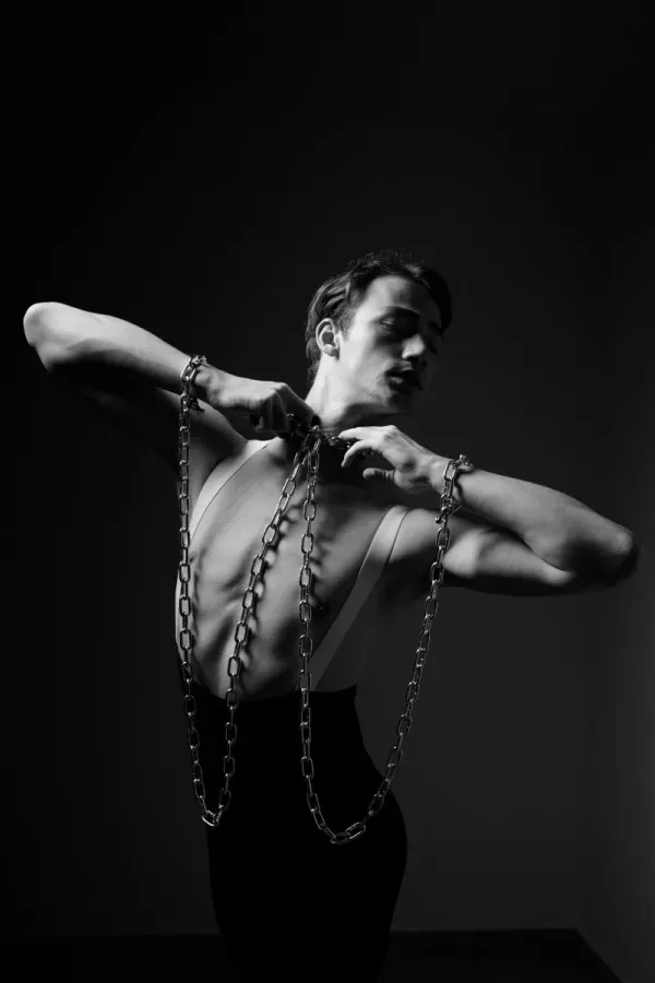 A high-contrast monochrome study of a male artist in a balletic pose of resistance, symbolizing the psychological landscapes of the human condition and creative liberation.